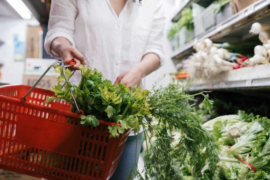 close up shot of a person holding a grocery basket with vegetables