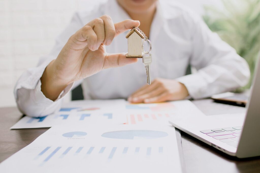 a person in long sleeve shirt holding keys and house key chain with his hands